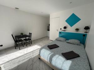 Un dormitorio con una cama azul y una mesa en La maison de Giulia Menton, en Menton