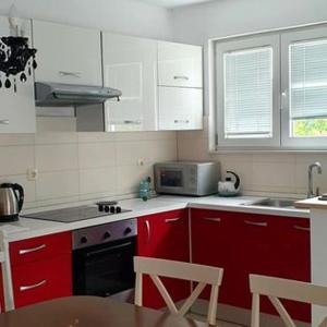 a kitchen with red and white cabinets and a microwave at Apartments Perina in Tisno