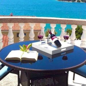 a table with two glasses of wine on a balcony at Apartments Perina in Tisno