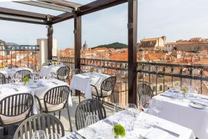 un ristorante con tavoli e sedie bianchi su un balcone di Boutique Hotel Stari Grad a Dubrovnik