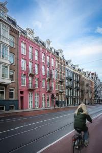 een vrouw op een fiets door een straat met gebouwen bij Krisotel in Amsterdam