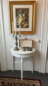 a white table with candles and a painting on the wall at The 1885 Suites in Picton