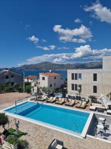 - une piscine avec des chaises longues à côté d'un bâtiment dans l'établissement Apartments Silva with a view of sea, à Trogir