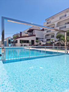 une piscine avec une clôture bleue et quelques bâtiments dans l'établissement Apartments Silva with a view of sea, à Trogir