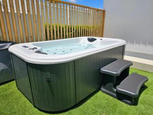 eine Whirlpool-Badewanne auf dem Rasen mit zwei Hockern in der Unterkunft MAR BIANCO - Gay Men Only in Maspalomas