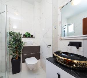 a bathroom with a sink and a toilet and a mirror at Urban Edge - Beach Apartments in Omiš