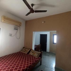 Schlafzimmer mit einem Bett und einem Deckenventilator in der Unterkunft Uthamar Illam in Tiruchchirāppalli