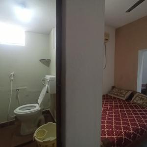 ein kleines Bad mit WC und ein Bett in der Unterkunft Uthamar Illam in Tiruchchirāppalli