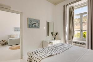 a white bedroom with a bed and a window at Hydra Hotel in Hydra