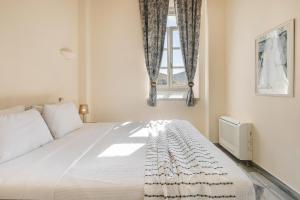 a bedroom with a large white bed with a window at Hydra Hotel in Hydra