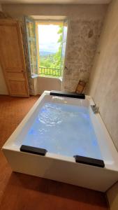 eine große Badewanne in einem Zimmer mit Fenster in der Unterkunft Domaine de la Cascade Parfumée in Grasse