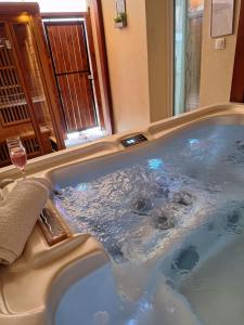 a tub with a glass of wine in a bathroom at Várfal apartman II in Eger