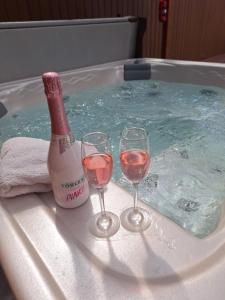 two glasses of wine and a bottle of champagne in a hot tub at Várfal apartman II in Eger