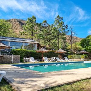 uma piscina com espreguiçadeiras e guarda-sóis em Aldea de los Pajaros em Villa General Belgrano