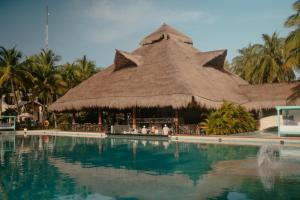 a resort with a large swimming pool with a thatch roof at El Dorado Casitas Royale Catamarán, Cenote & More Inclusive in Puerto Morelos