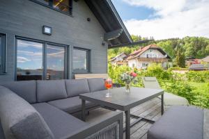 eine Terrasse mit einem Sofa und einem Tisch mit Weingläsern in der Unterkunft Hideaway Kraftplatz Chalet am See Mattsee Obertrum Urlaub am See Salzburger Seenland in Obertrum am See