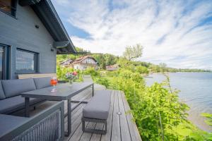 eine Terrasse mit einem Tisch und Stühlen sowie Blick auf das Wasser in der Unterkunft Hideaway Kraftplatz Chalet am See Mattsee Obertrum Urlaub am See Salzburger Seenland in Obertrum am See