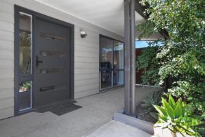 una casa con una puerta negra y ventanas en Recharge in Waurn Ponds, en Geelong