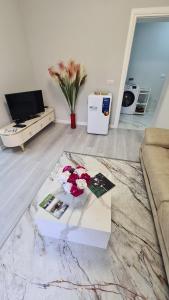 a living room with a table with flowers on it at Dei Cozy Apartment in Shkodër