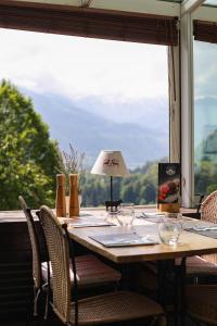 a table with chairs and a lamp in front of a window at Le Saint Georges in Gruyères