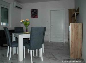 a dining room table with chairs and a vase of flowers at Apartman Soko 2 in Soko Banja