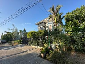 a house with a palm tree in front of a street at Bella Homes 6BR 4Bath near Rotunda in Tagaytay