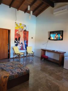 ein Wohnzimmer mit einem TV, einem Tisch und Stühlen in der Unterkunft Brisa da Serra Hotel Pousada Pirenopolis in Pirenópolis