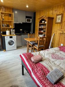 a bedroom with a bed and a table and a kitchen at Apparemment cosy style savoyard in Bourg-Saint-Maurice