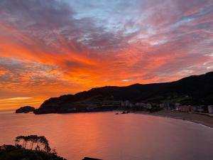 una puesta de sol sobre una playa con una montaña en El BALCON DE BAKIO, en Bakio