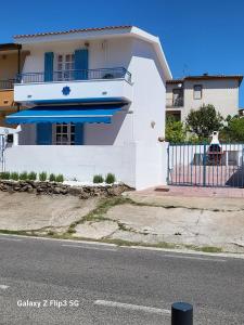 una casa bianca con una veranda blu e una recinzione di SPLENDIDA VILLA a POSADA a Posada