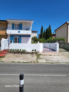 una casa bianca con un palo bianco e nero per strada di SPLENDIDA VILLA a POSADA a Posada