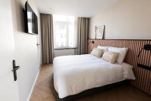 een slaapkamer met een groot bed met witte lakens en kussens bij Stadsherberg de Poshoorn in Maastricht