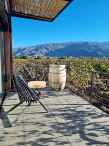 einen Tisch und einen Stuhl auf einer Terrasse mit einem Weinfass in der Unterkunft El Porvenir Wine Lodge in Cafayate