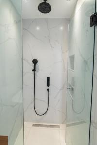 a shower with a glass door and a shower head at Olea Apartments Palioura Epanomi in Epanomi