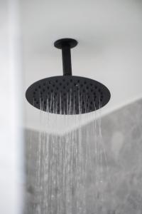 a shower with a black shower head with water at Olea Apartments Palioura Epanomi in Epanomi