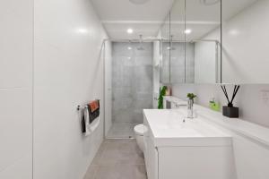 y baño blanco con lavabo y ducha. en Lifestyle Location - WIFI Included, en Newcastle