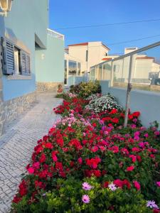 un jardin de fleurs rouges et roses à côté d'un bâtiment dans l'établissement Villa da Praia, à Sintra