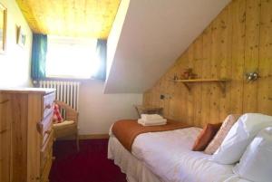 een slaapkamer met een bed met een houten muur bij Rond Point d Arbois in Megève