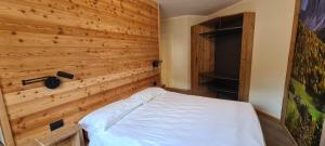 a bedroom with a wooden wall with a bed at Appartamenti Home Service in Arabba