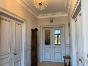 um corredor com uma porta branca e um lustre em Château de Ligny em Ligny-le-Châtel