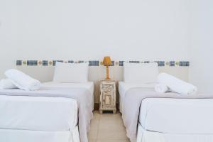 Cette chambre comprend 2 lits avec des draps blancs et une table. dans l'établissement Pousada Porto Fino, à Cabo Frio