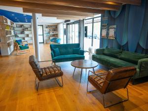 een woonkamer met een bank, stoelen en een tafel bij Mercure Mont Saint Michel in Le Mont Saint Michel