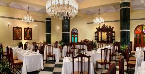 een eetkamer met witte tafels en stoelen en kroonluchters bij The Grand Imperial - Heritage Hotel in Agra