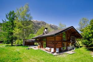 ein Blockhaus auf einem Feld mit Bergen im Hintergrund in der Unterkunft Chalet Taconnaz - Warm & Cosy 3BR Chalet with Fireplace in Nature - By Cozee Rentals in Les Houches