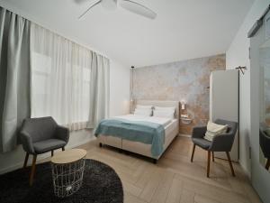 um quarto com uma cama, 2 cadeiras e uma mesa em Hotel Siebzehn80 em Carolinensiel