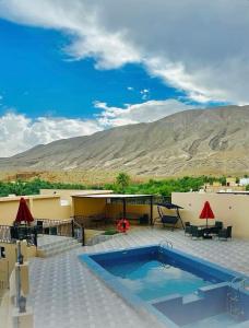 un complexe avec une piscine et des montagnes en arrière-plan dans l'établissement WADI BANI KALED REST HOUSE, à Dawwah