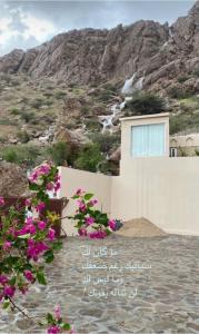 une maison avec des fleurs roses en face d'une montagne dans l'établissement WADI BANI KALED REST HOUSE, à Dawwah