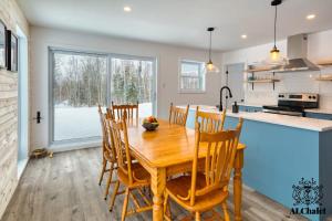 una cucina e una sala da pranzo con tavolo e sedie in legno di Le Loonix- Chalet familiale avec Spa a Petite-Rivière-Saint-François