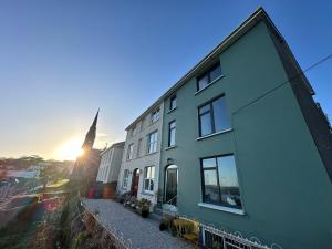 un edificio con el sol en el fondo y una iglesia en Westways House, en Cobh