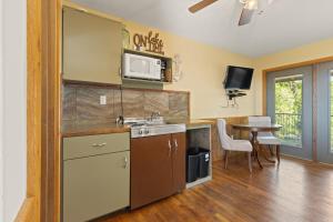 a kitchen with a sink and a microwave and a table at Roadrunner Inn and Log Cabins in Eureka Springs